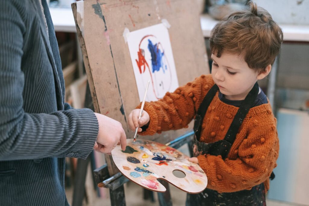 boy in orange and black zip up jacket holding white and red floral round plate 6816531